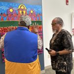 Two people standing and looking at a large painting on the wall
