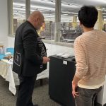 Picture of two people from behind looking down at a printer