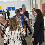 Group of people standing around talking and smiling
