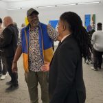 Two people standing and facing each other in an art gallery