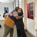 Two people hugging and smiling in an art gallery