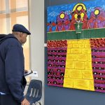 Man looking at a painting on the wall in an art gallery
