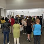 A large crowd of people in an art gallery
