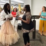 Tiffany standing in an art gallery talking and greeting other women