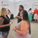 People standing around in an art gallery with snacks and talking