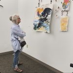 Women standing with her arms crossed looking at art on the wall
