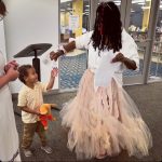 Tiffany Thomas handing a sticker to a little child in the library