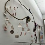 Art piece including flower petals hanging from sticks