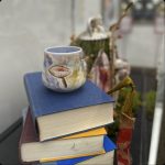Art piece of stacked books with a mug on top of the stacked books