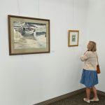 Woman standing close to art on the wall in an art gallery.