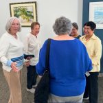 Women standing around in a circle in an art gallery.