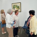 Women standing in a circle talking in an art gallery