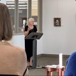 Lady standing at a podium speaking to an audience