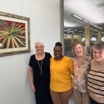 Jane Jackson with friends, new and old, standing next to art on the wall