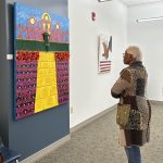 Side view of a person standing and looking at art on the wall in a gallery
