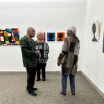 Group of people standing in a circle and talking in an art gallery