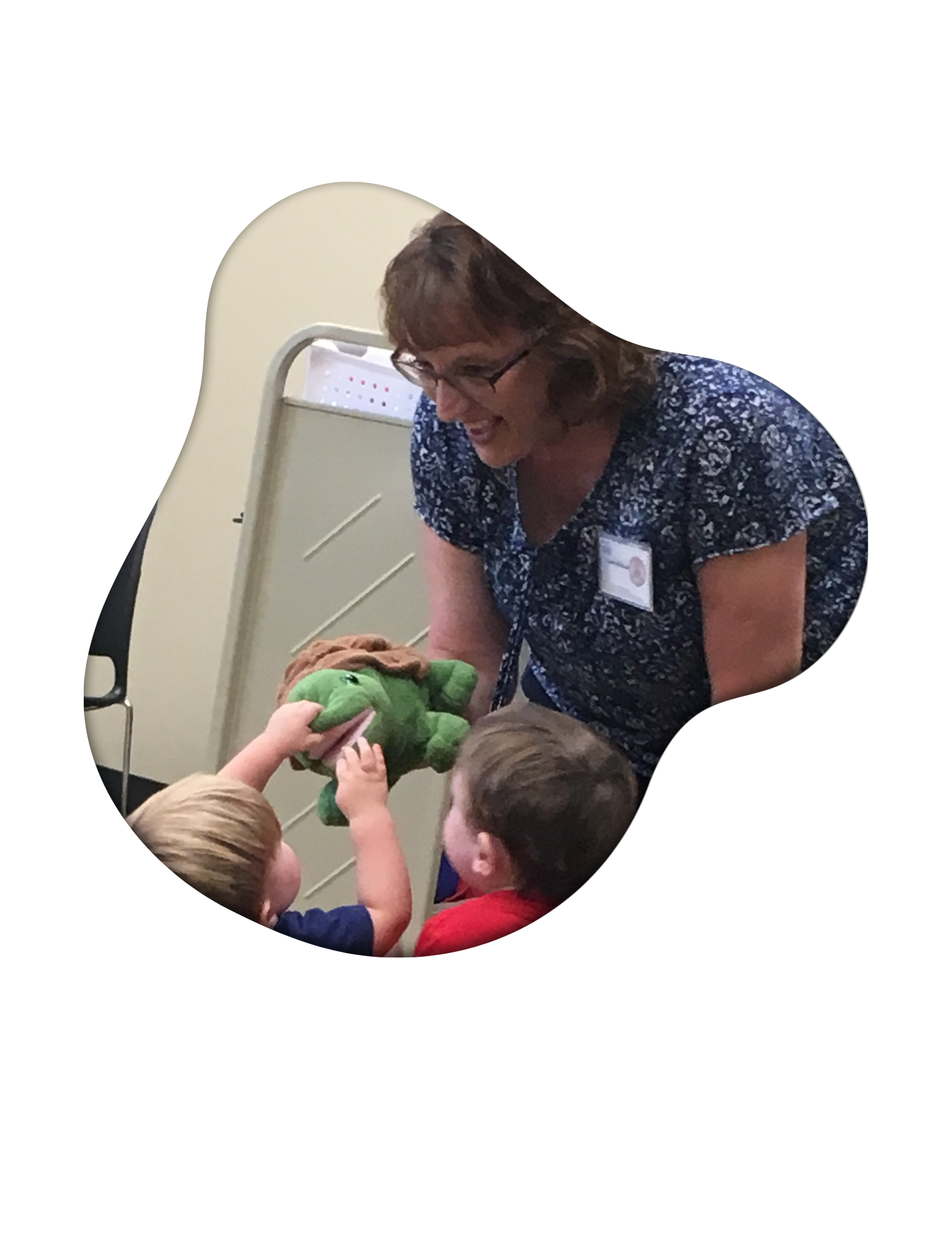 Lady with glasses showing a toy turtle to two little boys