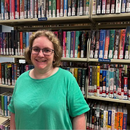 Photo of staff member Julie in front of book shelves