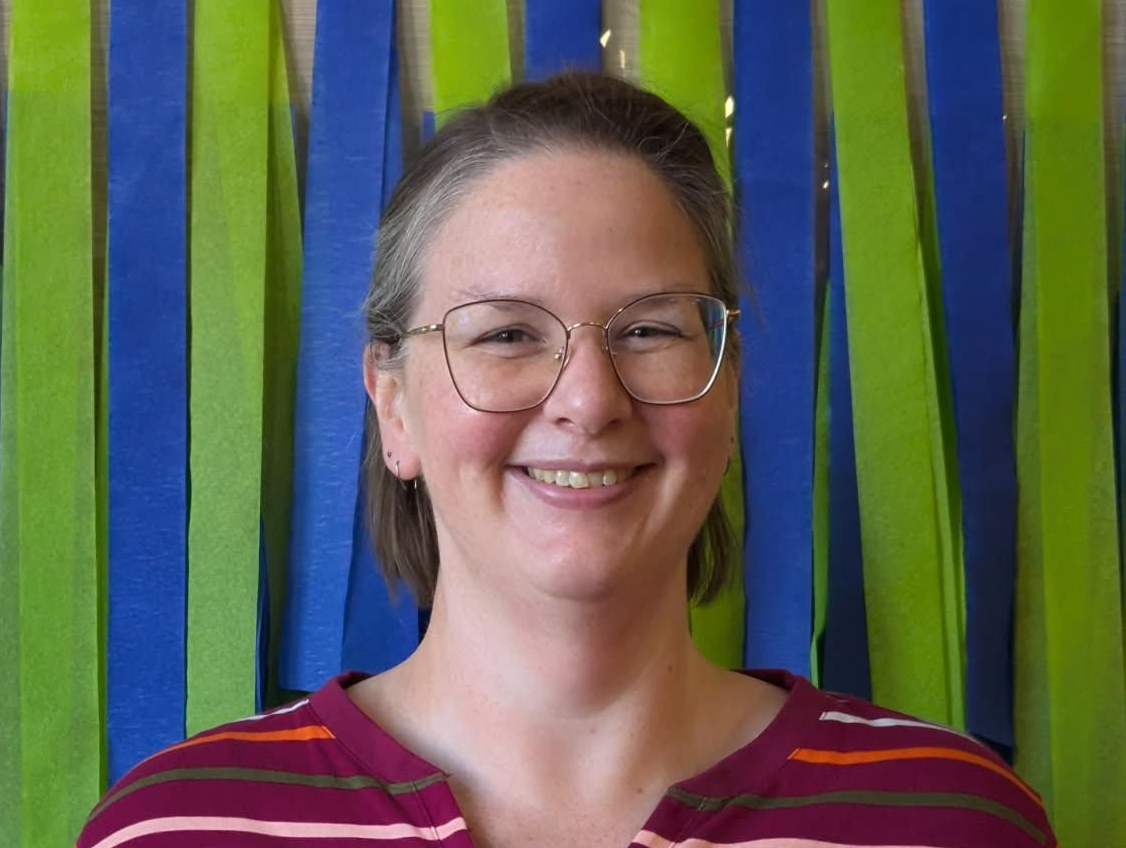 Headshot of Rachel, lady with light brown hair and glasses, smiling