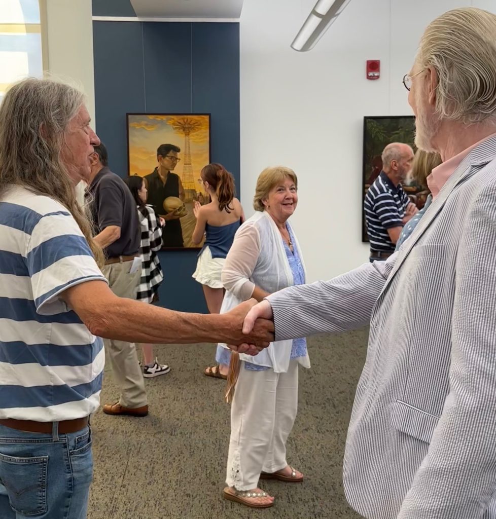 Two men shaking hands and a lady in the background