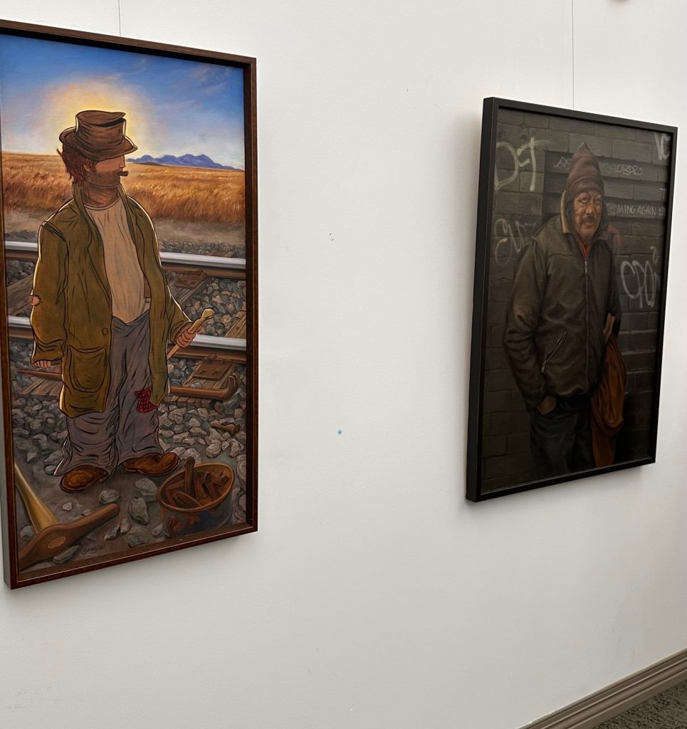 paintings of hobo and solitary man hung on wall