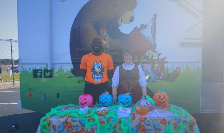 Librarians standing behind pumpkins lined up on a table