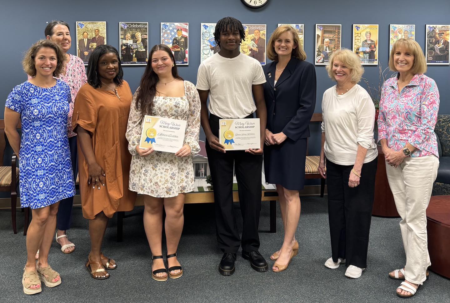 two high school students holding their scholarship awards surrounding by other adults