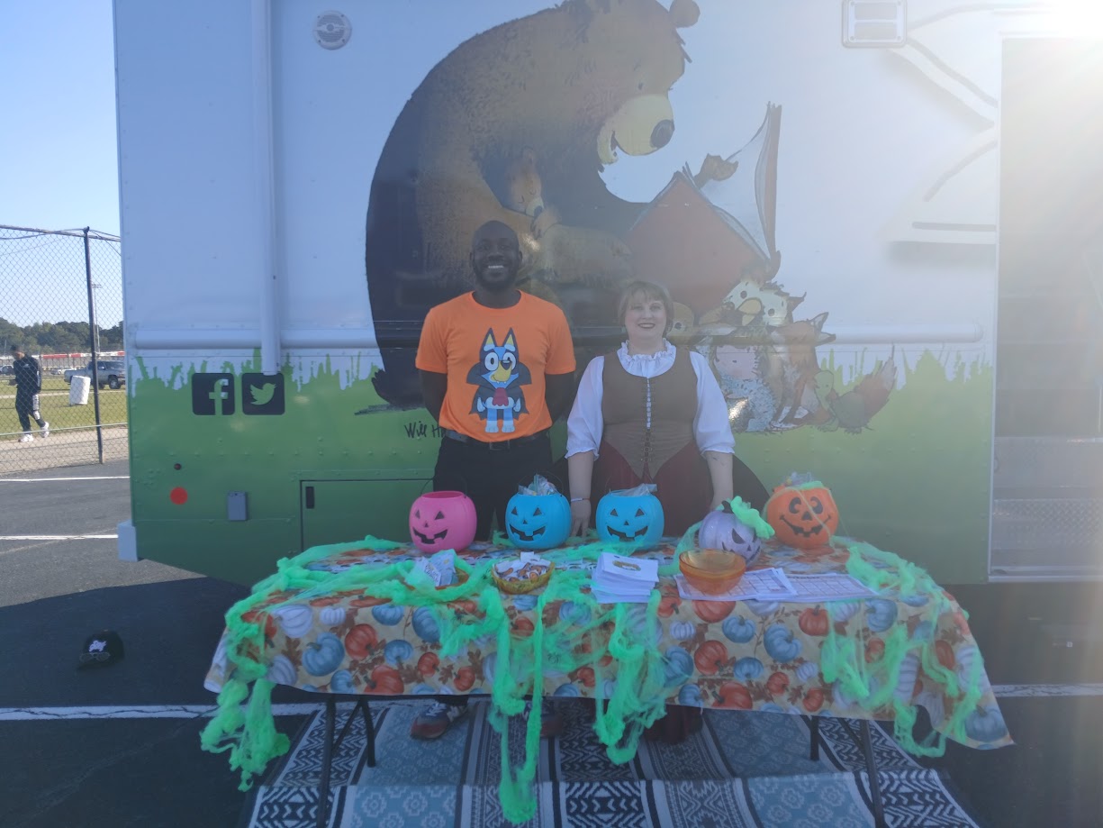 Librarians standing behind pumpkins lined up on a table