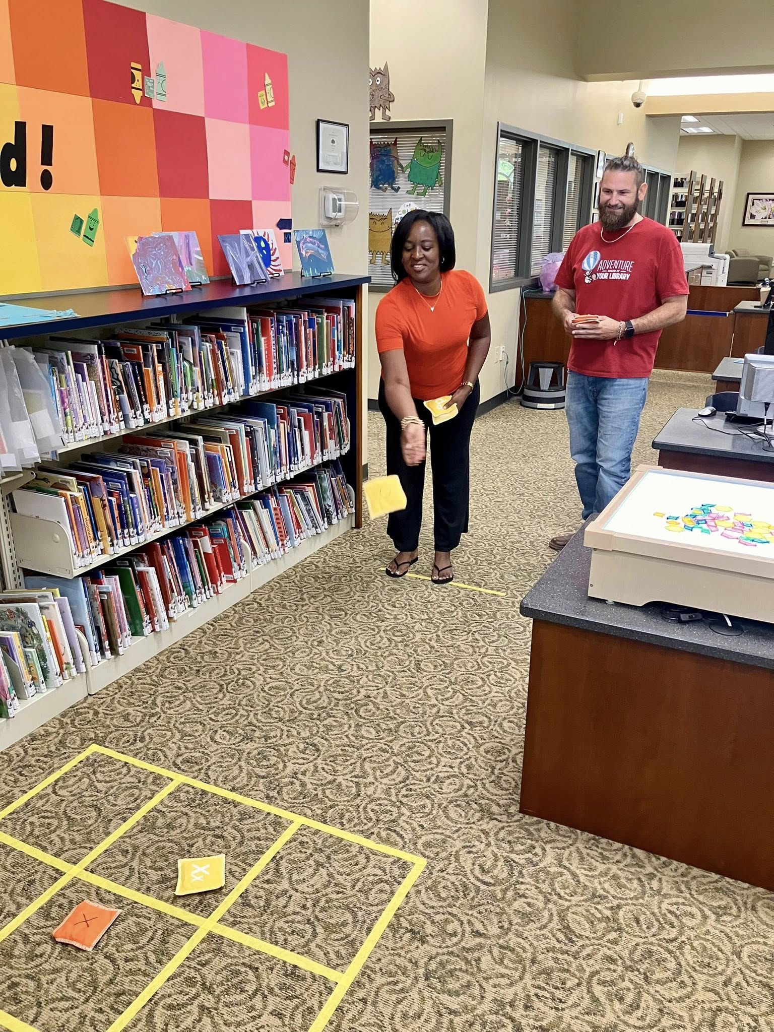 Two coworkers playing a bean bag game