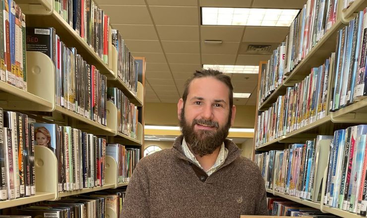 Granger Britt headshot standing in a row of books