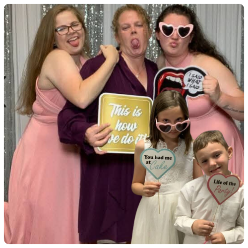 Penny in a photo booth with family holding up props