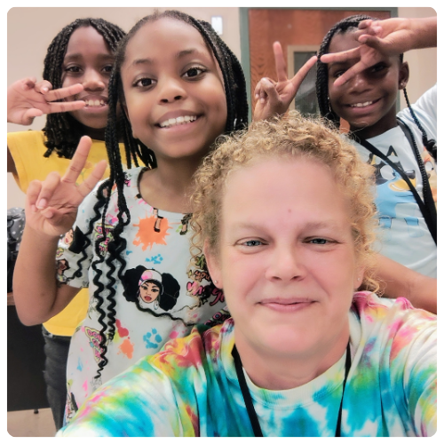 Penny with children holding up peace signs