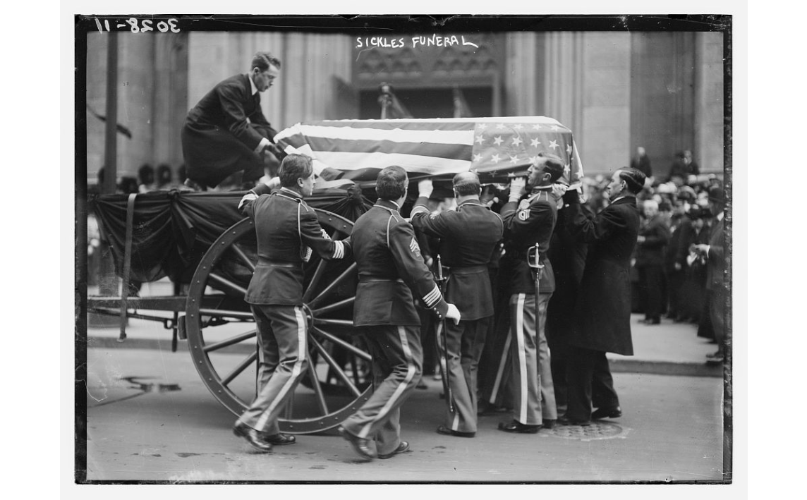 Men gathered around a casket with American flag draped over it