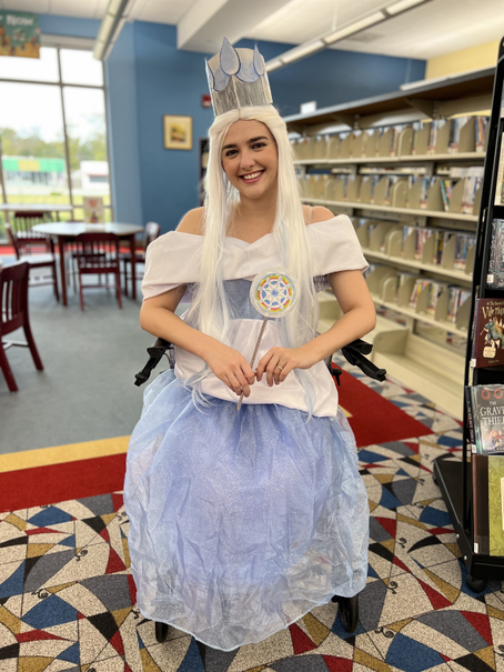 Mikaela dressed in a blue and white dress with a white wig, crown, and wand