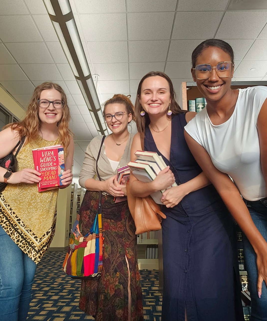 Mikaela and three friends holding their books at the library