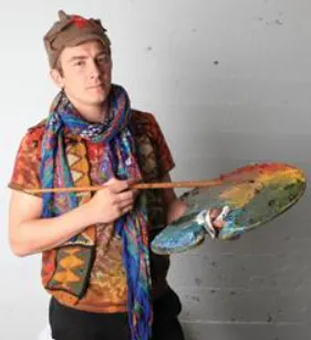 Photo of male holding artist palette and paintbrush