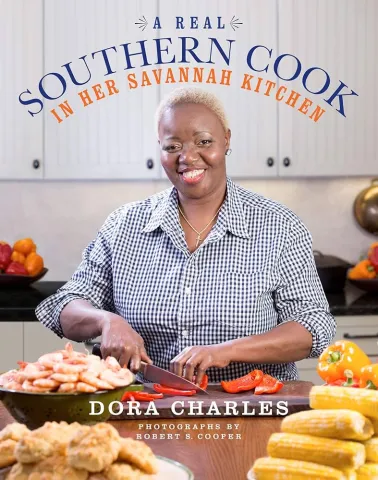 Cover for the cookbook "A Real Southern Cook In Her Savannah Kitchen Dora Charles" with a picture of the author in a kitchen