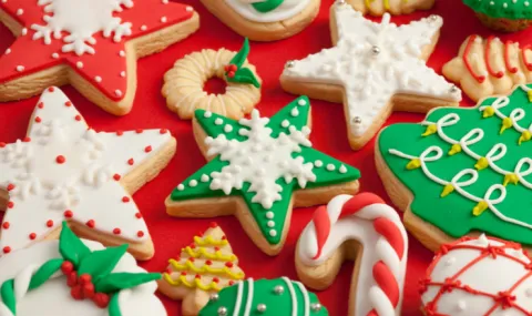 Various colorful cut out and iced Christmas cookies on a red background