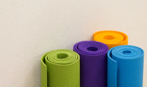 Four yoga mats rolled up against a wall