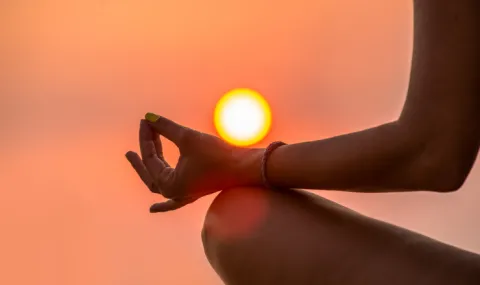 A person sitting in a meditative pose in front of a sunrise