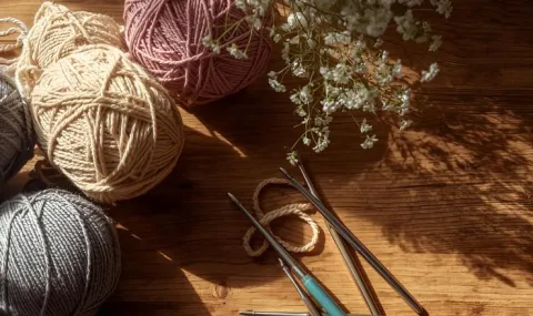 Skeins of yarn, crochet hooks, and some flowers