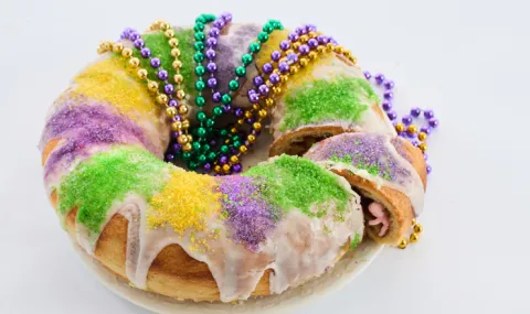 A round king cake with colorful beads on a gray background