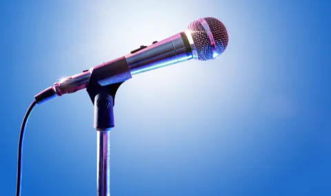 A microphone in front of a blue background and spotlight