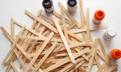popsicle sticks scattered around with bottles of paint next to them