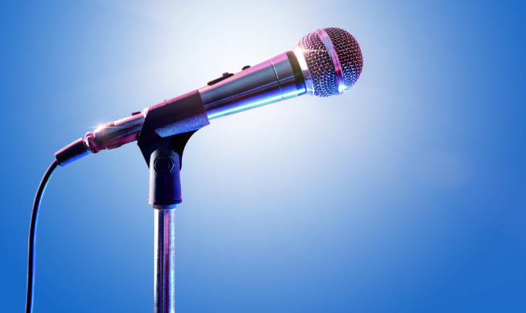 A microphone in front of a blue background and spotlight