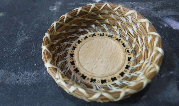 A woven pine needle basket on a dark background