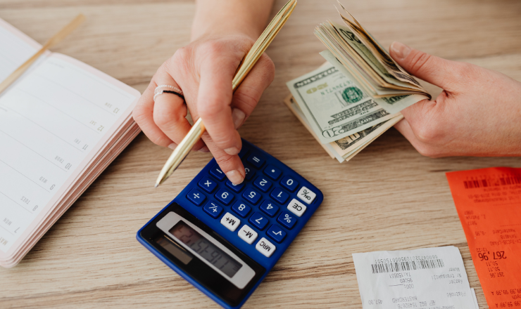 A person with money and receipts balancing a spending budget with a calculator