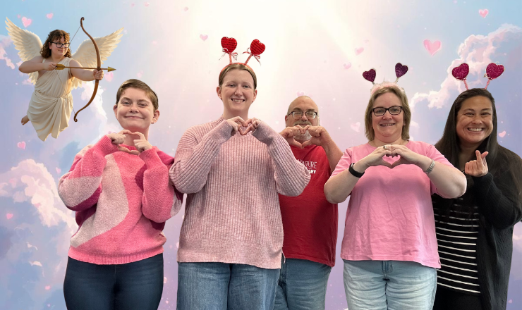 Group of writers holding up their hands in heart shapes with one floating as a cupid in the corner